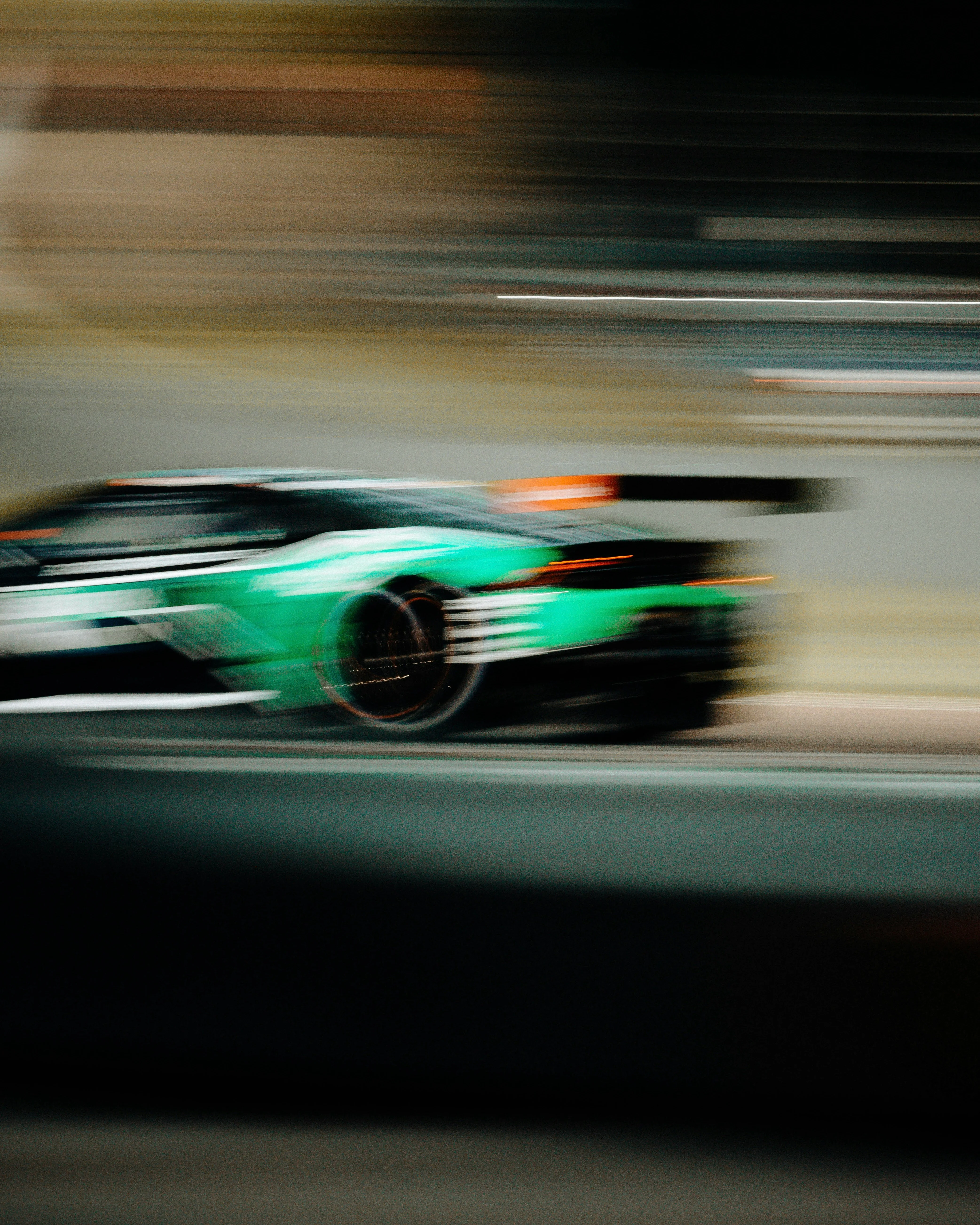 Green race car at speed on track